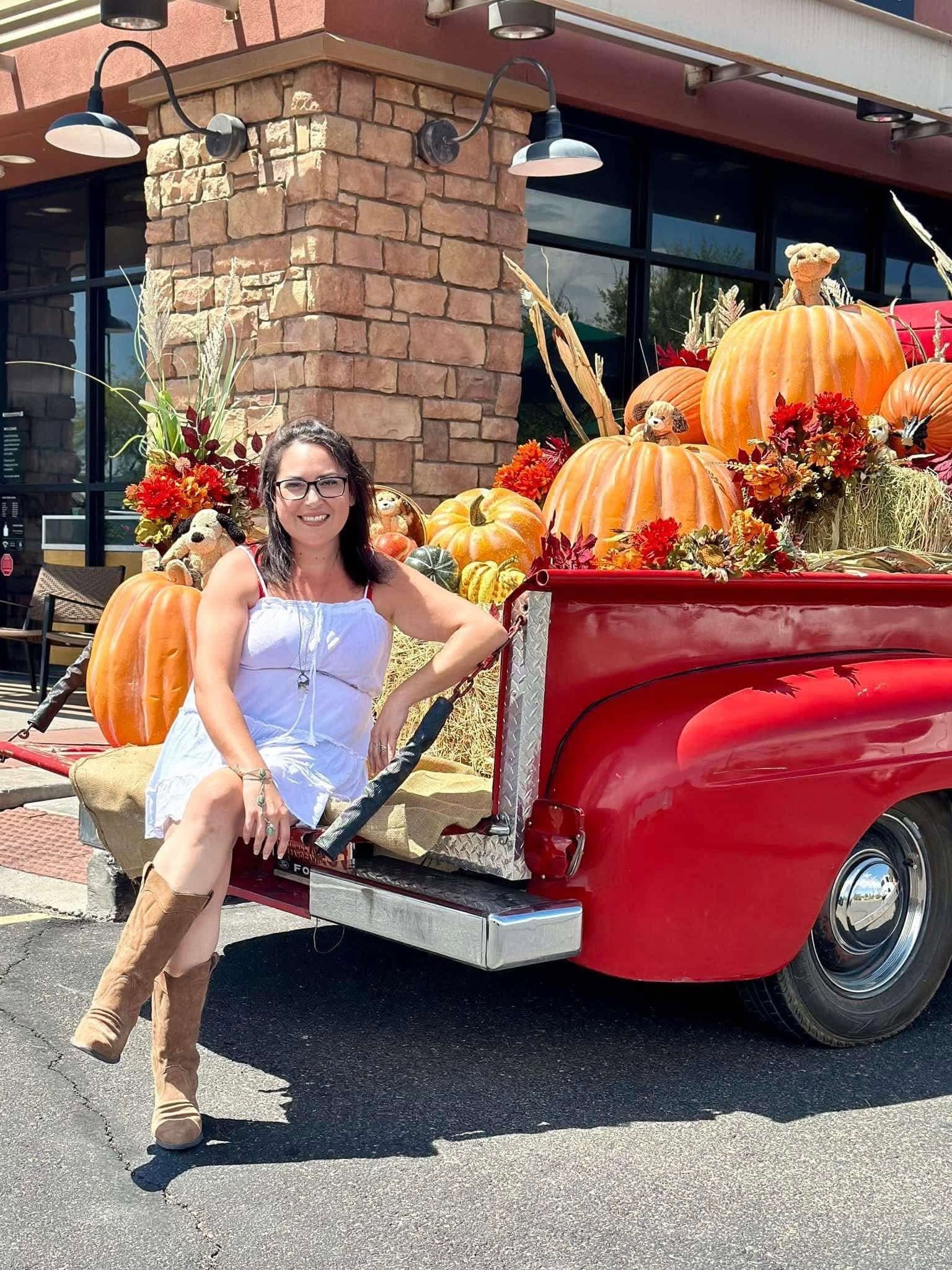 The creator of Good Vibes Cooking beside a vintage red truck and autumn pumpkins